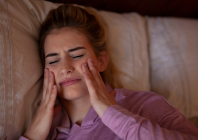 Woman experiencing jaw and facial discomfort from nighttime teeth grinding, highlighting common symptoms that may require treatment to fix grinded teeth and prevent further wear.
