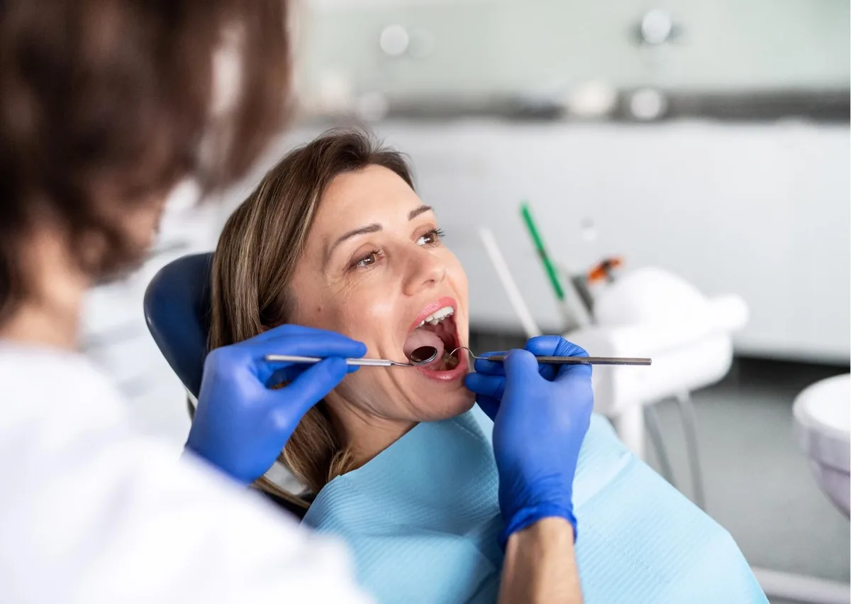 Dentist examining a patient’s teeth as part of maintaining dental implants for long-term use.