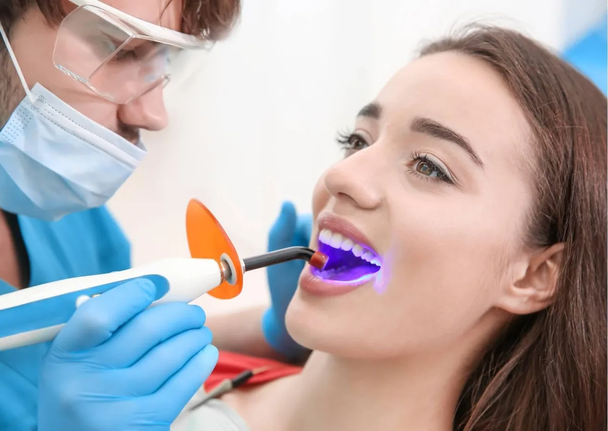 Dentist using a curing light during a teeth bonding procedure.