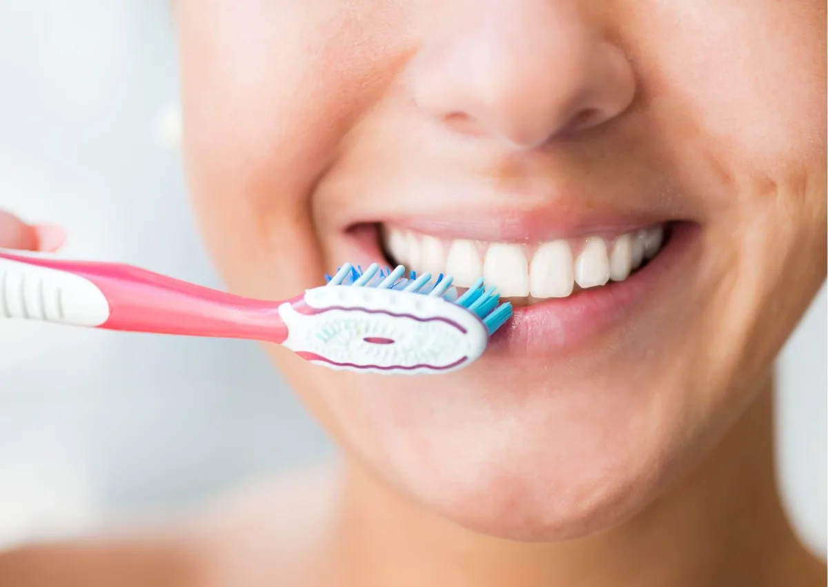 Person brushing their teeth, illustrating daily care after teeth bonding.