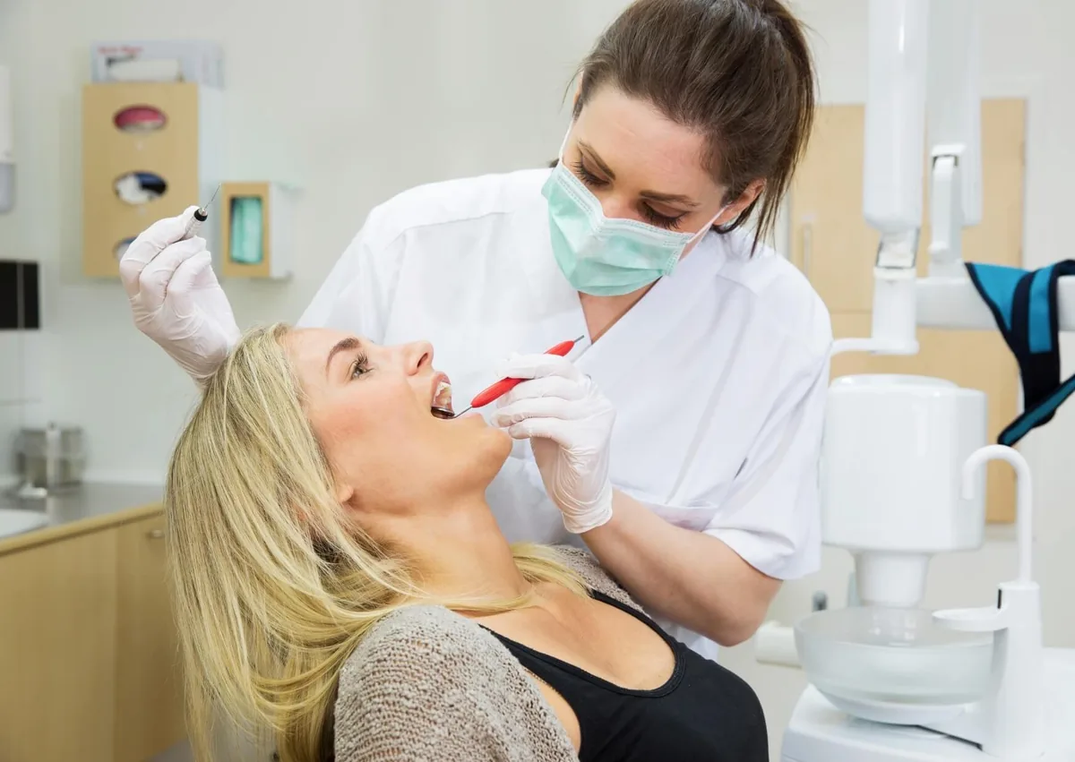 Dentist examining a patient’s teeth while discussing dental sealants, treatment needs, and cost.
